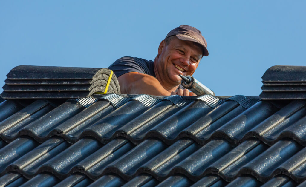 man smiling and fixing a roof 