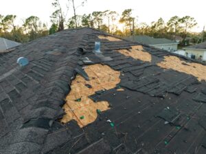 Black Denver roof damaged by hail with exposed wood